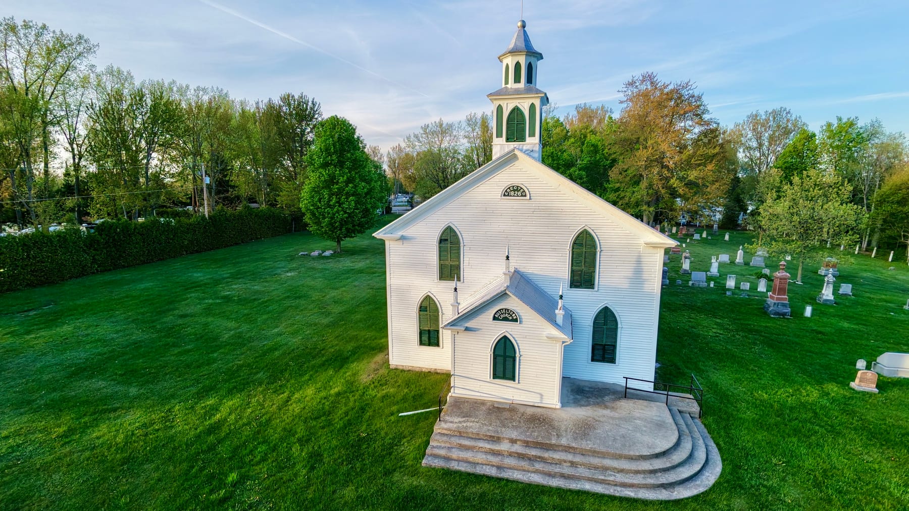 Vue aérienne de l'église unie de Russeltown à Saint-Chrysostome, église de bois blanche et son cimetière, au soleil couchant